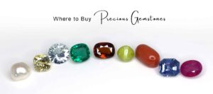 Certified gemstones of various colors and shapes arranged in a line on a white background